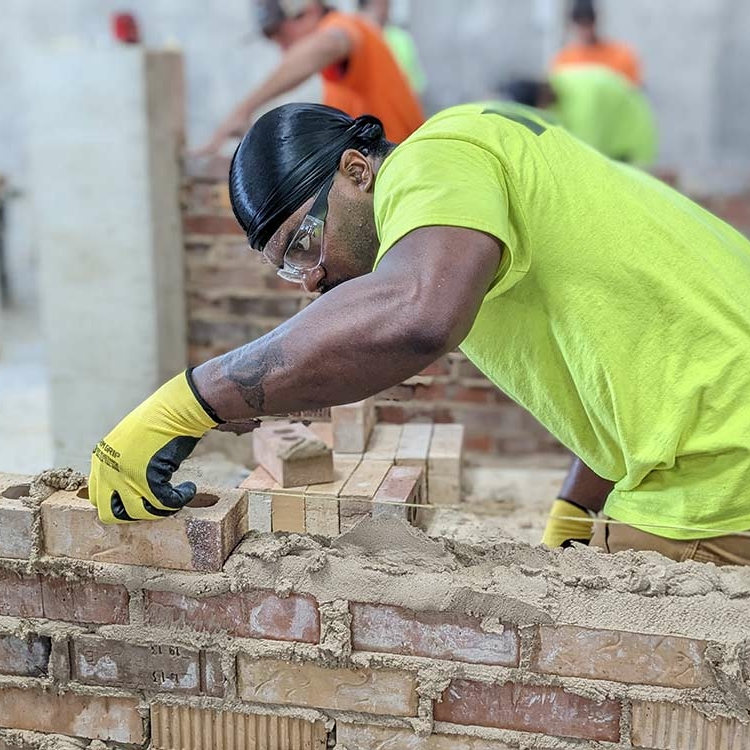 Pre-apprentice worker building with bricks